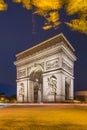 Arc de Triomphe at dusk in Paris in France with traffic of cars light trails and yellow leafs moved by the wind