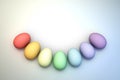 An Arc of Pastel Rainbow Colored 3D Illustrated Easter Eggs over a Bright Background.