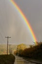 Arc of rainbow above a wet country road Royalty Free Stock Photo