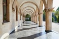Arcade and a corridor of white columns on one side and walls on the other. A passage of marble columns outside and green plants in Royalty Free Stock Photo