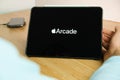 Arcade logo on the screen of the IPad tablet with charging smart phone on the wireless charger on the wooden table