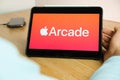 Arcade logo on the screen of the IPad tablet with charging smart phone on the wireless charger on the wooden table