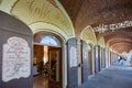 Arcade in red bricks around Sanctuary of Vicoforte church with people and shops in Italy