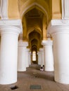 An arcaded corridor with tall, white columns and yellow arches at the ancient Tirumalai