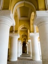 An arcaded corridor with tall, white columns and yellow arches at the ancient Tirumalai Royalty Free Stock Photo