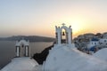 Arch with a bell, white houses and church with blue domes in Oia or Ia at golden sunset, island Santorini, Greece. - Immagine Royalty Free Stock Photo