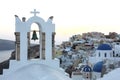 Arch with a bell, white houses and church with blue domes in Oia or Ia at golden sunset, island Santorini, Greece. - Immagine Royalty Free Stock Photo