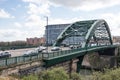 Arch bridge with car traffic crossing river. Metal arch Victorian construction