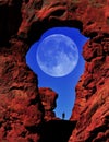 Arch in Canyon Red Rock Formations Silhouette of Hiker with Full Moon in Sky Royalty Free Stock Photo