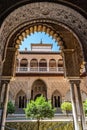 Arch with engraved decoration and polylobed arch framing the building and courtyard inside the Real AlcazÃ¡r, Seville SPAIN Royalty Free Stock Photo