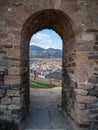 Arch gate in ancient medieval stone castle wall with view at small town and mountains Royalty Free Stock Photo