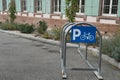 Arch metal frame for parking bicycles with blue sign containing letter P and pictogram of bicykle situated on the street.