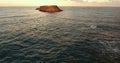 Stone island in the sea. Flight of the camera to the island at sunset.