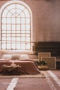 Arch window in a wabi sabi bedroom interior with a bed and iron radiator