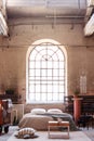 Arch window in a wabi sabi bedroom interior with a bed, raw walls and table