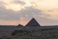 Archaeological complex of Great Egyptian Pyramids is located on the Giza plateau. the night light at sunset. sun sets behind the Royalty Free Stock Photo