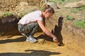 Archaeologist girl aligns the wall and bottom of the excavation with a spatula Royalty Free Stock Photo