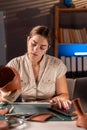 Archaeologist working in office using laptop and studying antique old vase Royalty Free Stock Photo