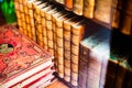 Archaic prop hardcover books aligned on a wooden shelf closeup. Old literature reading and collecting antique shop abstract