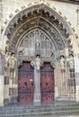 Arched antique wooden door with black iron ornaments in a stone wall. Basilica Minor of Saint Benedict in Hronsky Benadik