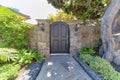 Arched black front door gate in the middle of two wall posts with lamps and doorbell