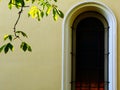 Arched church window detail in yellow stucco elevationwith autumn horse chestnut tree leaves Royalty Free Stock Photo