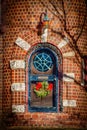 Arched door in turret of brick house with Christmas lights and round stained glass window and holiday wreath Royalty Free Stock Photo