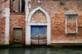 Arched entrance with wooden door of a venetian building on a canal, Venice
