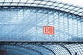 arched metal vault at train station, glass-enclosed platform with DB logo, representing modern railway infrastructure and branded