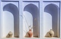 An arched niche in a white wall with old clay vases. Old aged pl