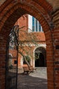 Arched red-brick entrance to the church with a tree inside the courtyard Royalty Free Stock Photo