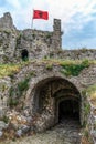 Arched tunnel in Shkoder Castle and Albanian flag among the fortress ruins Royalty Free Stock Photo