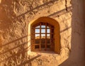 Arched window with lattice bars stone wall cast shadows warm sunlight Royalty Free Stock Photo