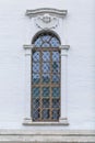 Arched window with onament and bars in a white brick building. Fortresses and historic houses. Vertical Royalty Free Stock Photo