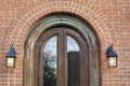 Arched window on a red brick building wall with lantern lamps on the side