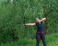 archery in nature. A young attractive woman is training in a bow shot with an arrow at a target in the woods