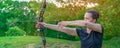 Archery in nature, young woman aiming an arrow at a target