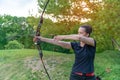 Archery in nature, young woman aiming an arrow at a target Royalty Free Stock Photo