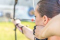 Archery, young woman with an arrow in a bow focused on hitting a target