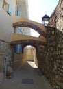 Arches connecting an old stone wall and a newer house over a narrow street on a hot summer day in Antibes