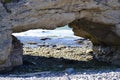 The Arches rock formation framing boulder filled beach with crashing waves