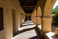Walkway through a cloister in an old Spanish mission church with thick stuccoed adobe walls, arches, and pillars