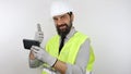 Architect wearing work helmet and reflecting jacket typing on smartphone, doing ok sign and smiling. Royalty Free Stock Photo