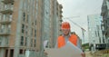 Architect or builder man walking on the construction site and analyzing scheme project plan. Young architect or builder