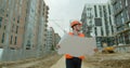 Architect or builder man walking on the construction site and analyzing scheme project plan. Young architect or builder