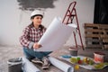 Architect builder studying layout plan of the rooms while sitting on the floor, serious civil engineer working with Royalty Free Stock Photo