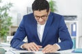 architect in casualwear sitting by table reading project Royalty Free Stock Photo