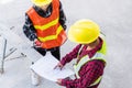 Architect and client discussing help create plan with blueprint of the building at construction site floor Royalty Free Stock Photo