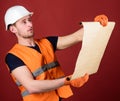 Architect concept. Engineer, architect, builder on strict face holds old blueprint in hands, supervises construction Royalty Free Stock Photo