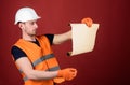 Architect concept. Man in helmet, hard hat holds building plan, controls works, red background. Engineer, architect Royalty Free Stock Photo